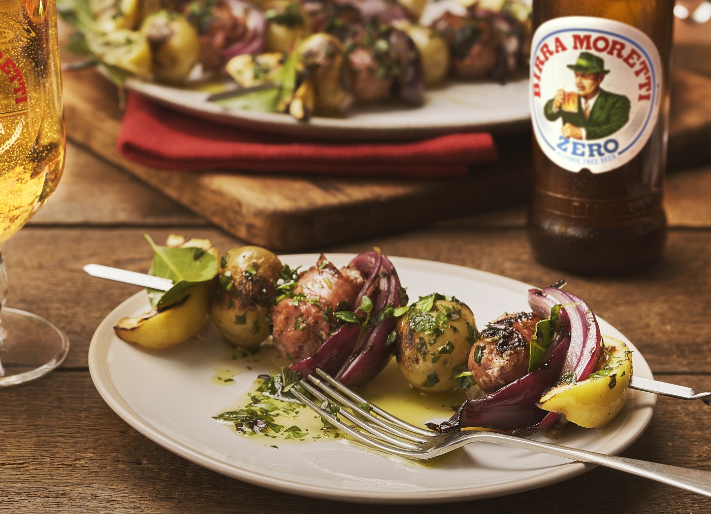 Skewer garnished with parsley and thyme, served alongside a bottle of Birra Moretti.