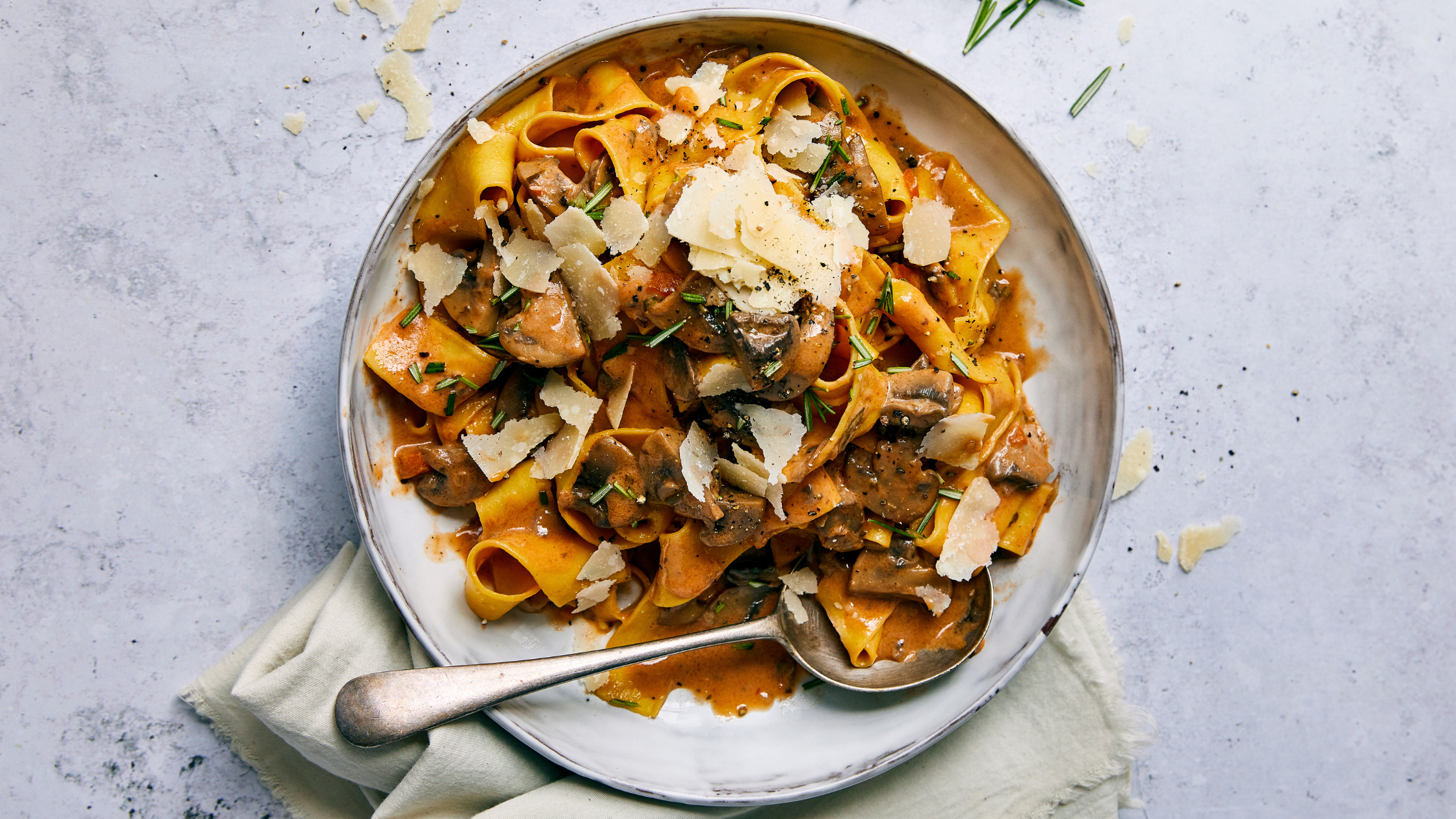 Tagliatelle in a creamy sauce topped with Parmesan flakes, served on a plate.