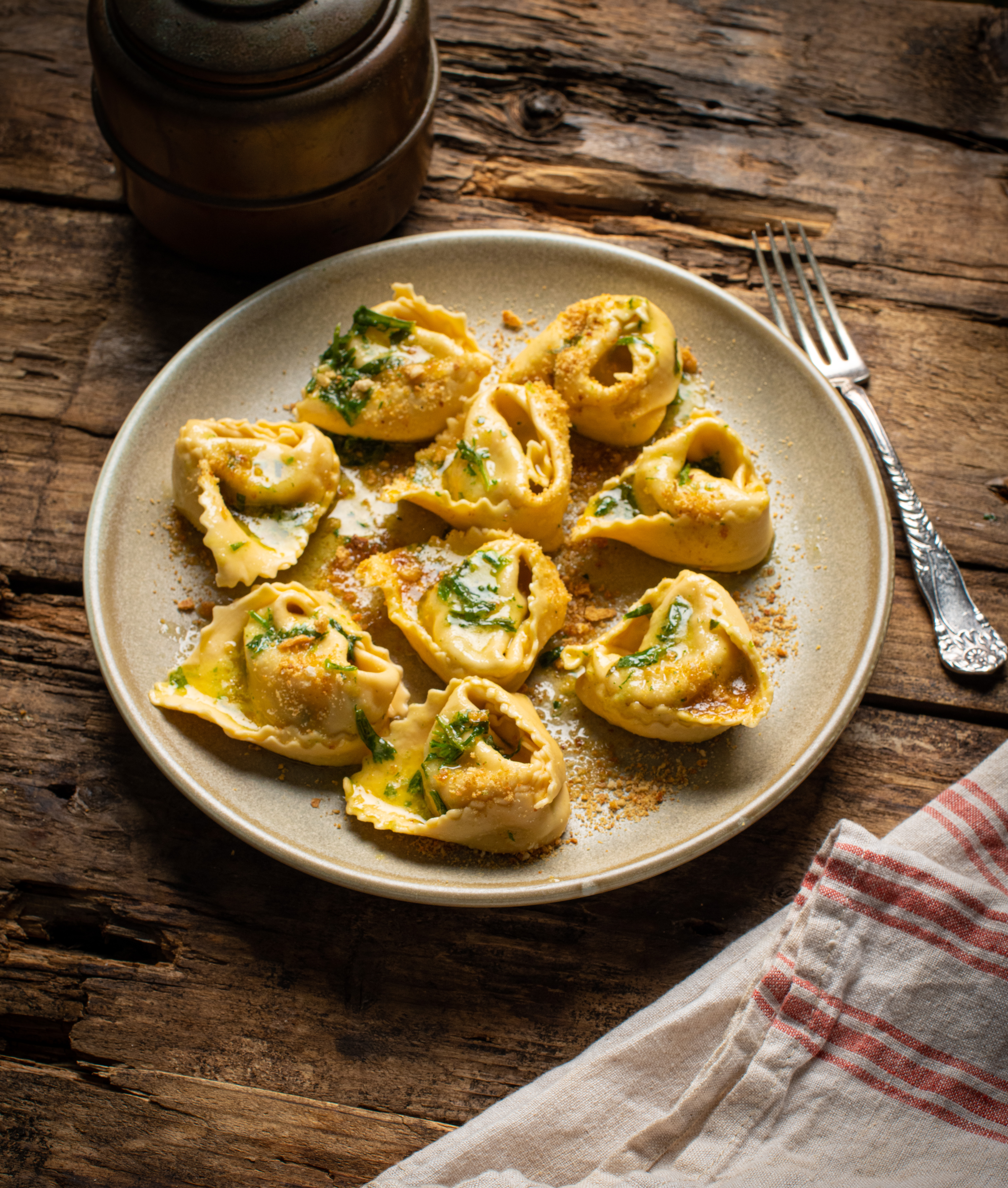 Tortelloni tossed in butter and served on a plate.” data-udi=